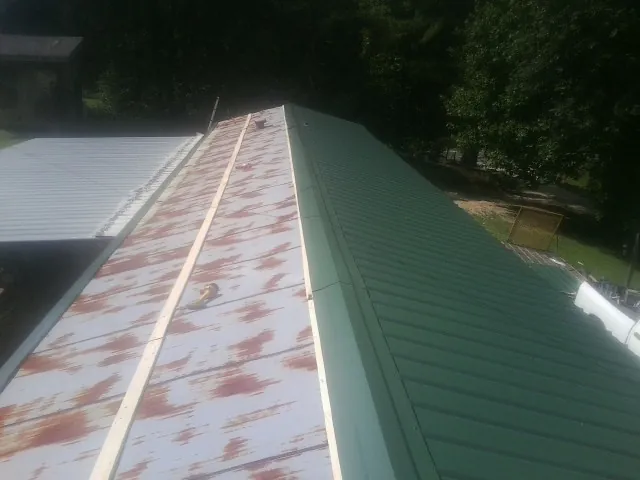Old rusted panels beside newly installed green metal roofing — Wind Damage Roof Repair by Roofing Brothers in Readyville