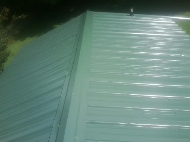 New green metal panels meeting at the ridge of a roof — Flat Roof Repair work by our crew in Readyville