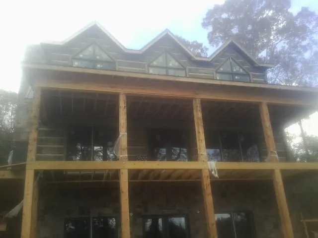 Dormers and porch framing on a large log home under construction — Roof Coating work by our crew in Readyville