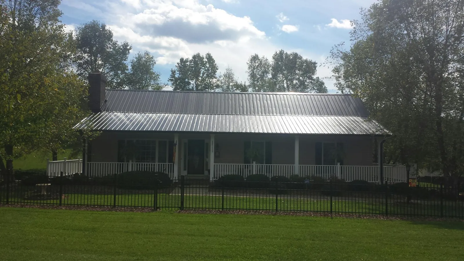 Gray metal roof on a brick ranch with a full width front porch — Gutter Guard Installation work by our crew in Readyville