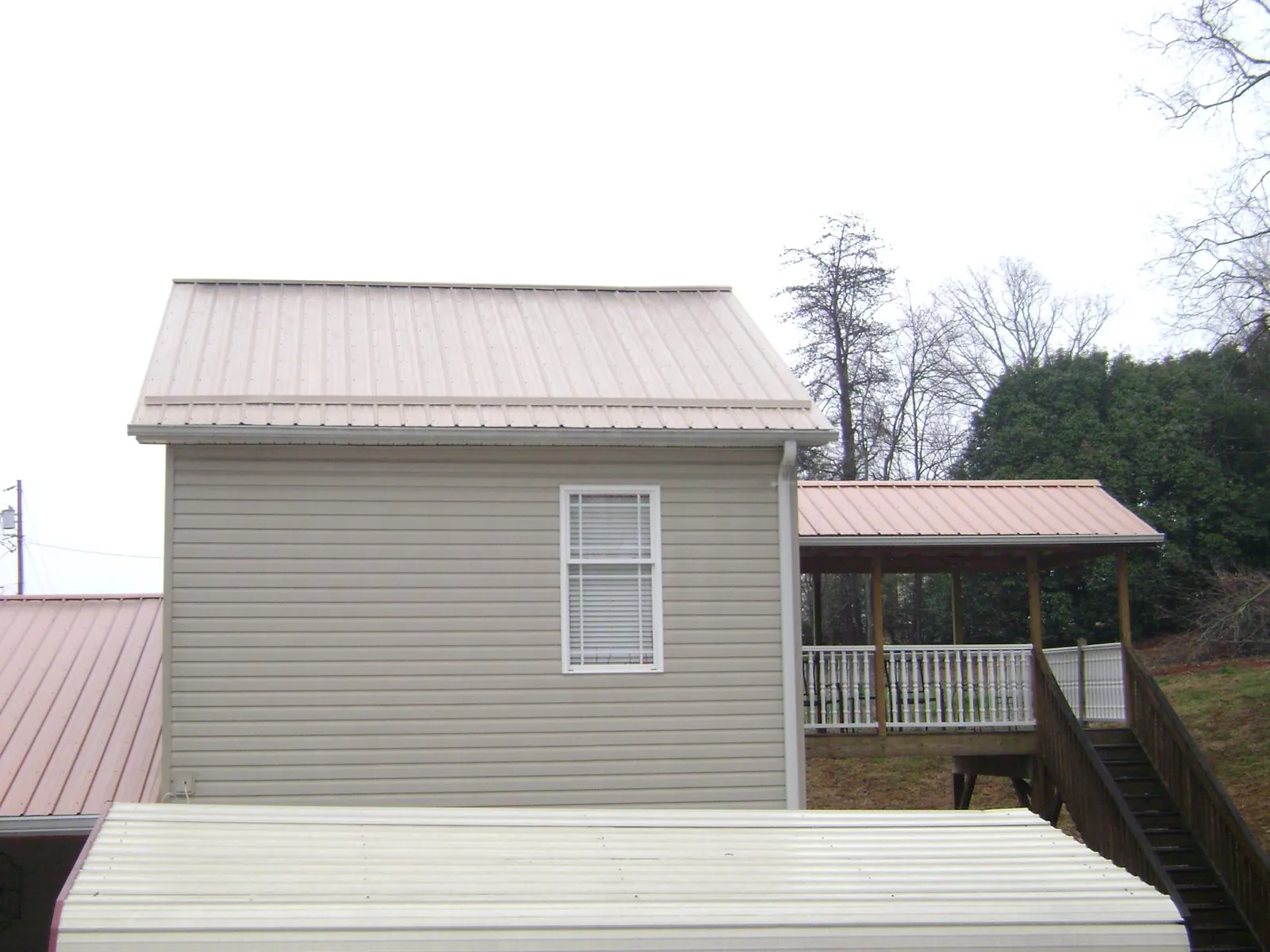 Tan metal roofs on a two story addition and attached porch, from a Roof Replacement job in Readyville