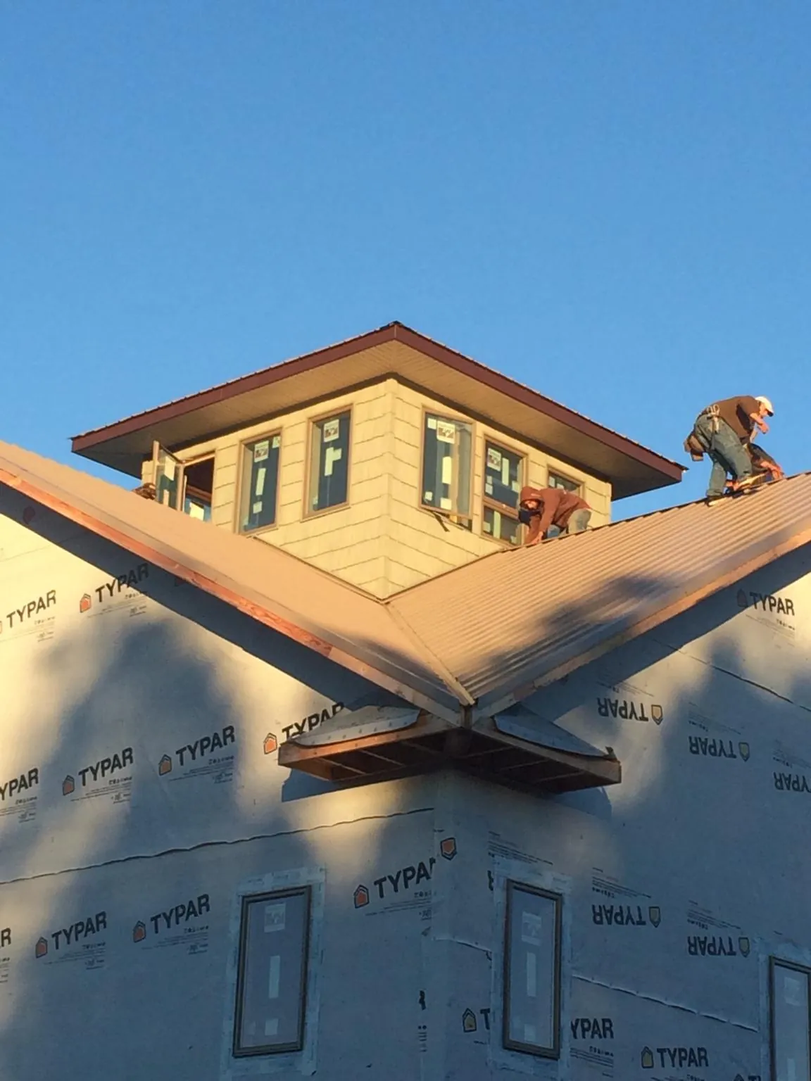 Roofers working around a rooftop cupola on a new metal roof at sunset — Roof Waterproofing in Readyville by Roofing Brothers